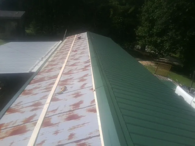 Old rusted panels beside newly installed green metal roofing — Wind Damage Roof Repair by Roofing Brothers in Pennsville