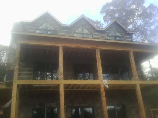 Dormers and porch framing on a large log home under construction — Roof Coating work by our crew in Pennsville