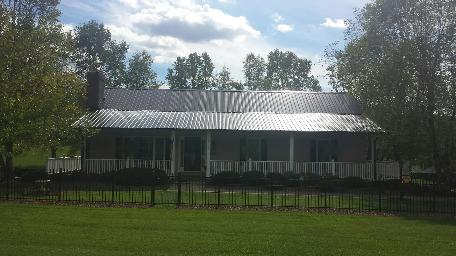Gray metal roof on a brick ranch with a full width front porch — Gutter Guard Installation work by our crew in Pennsville