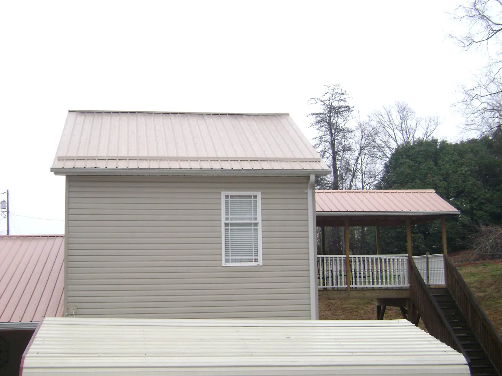 Tan metal roofs on a two story addition and attached porch, from a Roof Replacement job in Pennsville