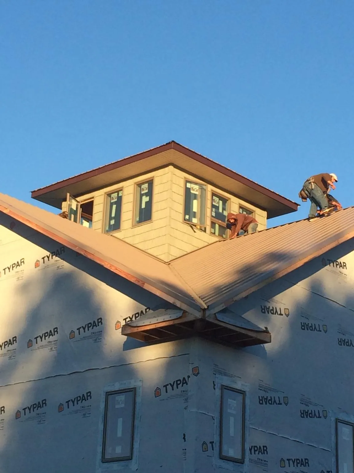 Roofers working around a rooftop cupola on a new metal roof at sunset — Roof Waterproofing in Pennsville by Roofing Brothers